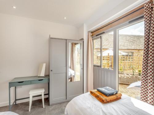a bedroom with a bed and a desk and a window at The Maltings - Uk44460 in Kingscote