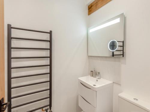 a white bathroom with a sink and a mirror at The Maltings - Uk44460 in Kingscote