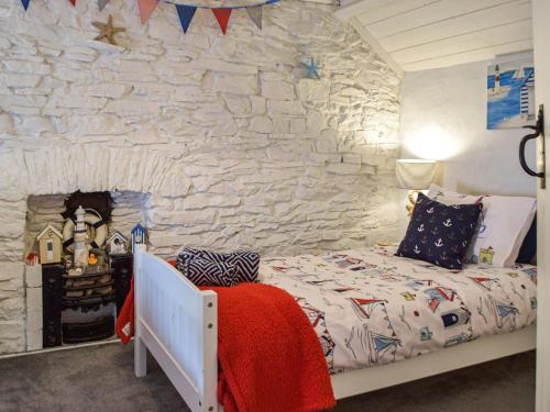 een slaapkamer met een bed en een stenen muur bij Penlan Cottage in Cwrt-newydd