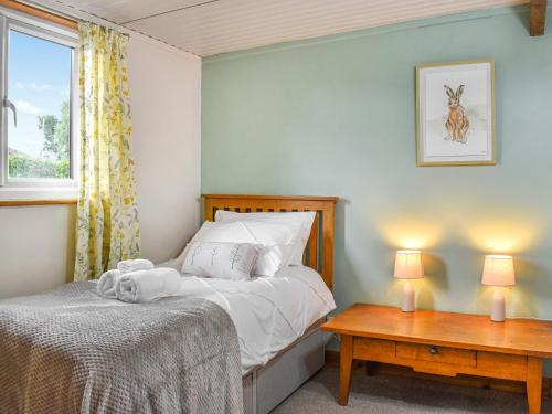a bedroom with a bed and a window and two tables at Newlyn Cottage in Pluckley