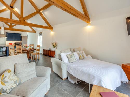 a bedroom with a bed and a couch and a table at The Granary - Uk44454 in Kingscote