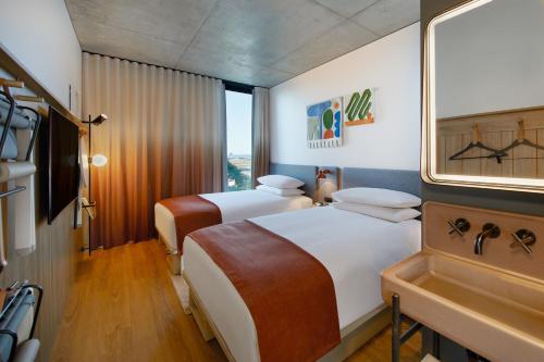 a hotel room with two beds and a sink at Moxy Sydney Airport in Sydney