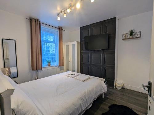 ドーバーにあるCharming 4-Bedroom House in Doverのベッドルーム(白いベッド1台、薄型テレビ付)