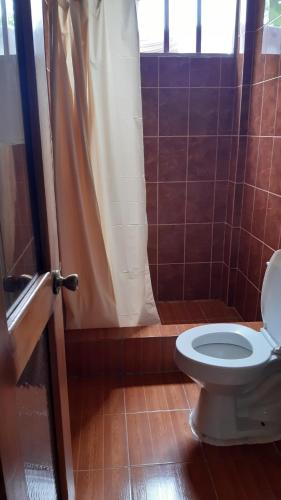 a bathroom with a toilet with a shower curtain at Alojamiento Same in Volcán Chimborazo