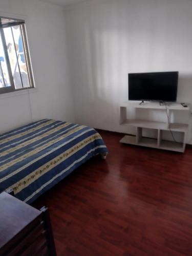 a bedroom with a bed and a flat screen tv at Hostal Ines in Santiago