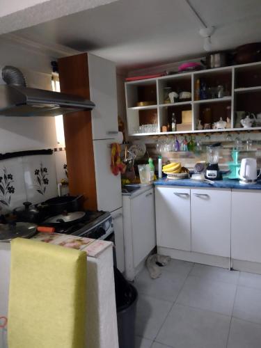 a small kitchen with white cabinets and a stove at Hostal Ines in Santiago