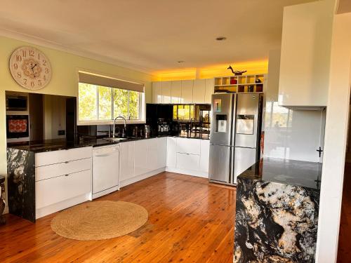 una cocina con armarios blancos y electrodomésticos de acero inoxidable en Mountain View, en Woombye