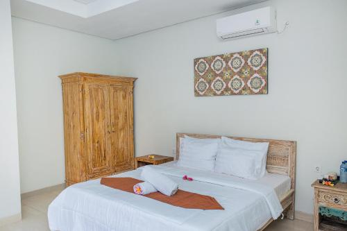 a bedroom with a white bed with a wooden cabinet at Pondok Raamshanti Lembongan in Nusa Lembongan