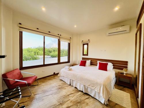a bedroom with a bed and a window and a chair at Lava Heron Galapagos Apartment in Puerto Ayora