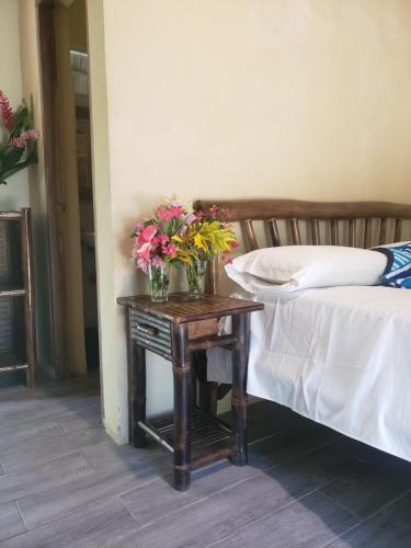 una mesa con flores junto a una cama en The Grand Mango, en El Gigante