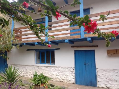 a house with blue doors and flowers at El Arriero Hostel B&B in Ollantaytambo