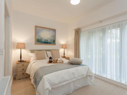 a white bedroom with a bed and a large window at The Stables in Cheriton