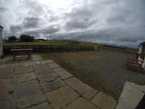 a park with two benches and a cloudy sky at Madras cottage Orkney Islands in Harray