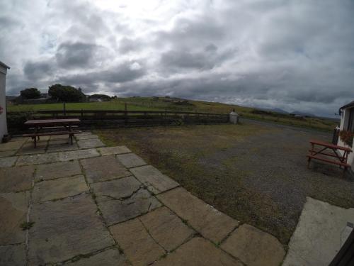 a park with two benches and a cloudy sky at Madras cottage Orkney in Harray