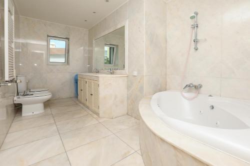 een badkamer met een bad, een toilet en een wastafel bij Yo-House in Costa da Caparica