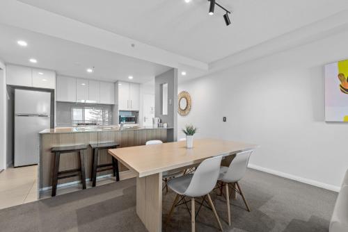 a kitchen with a wooden table and chairs at Proximity Waterfront Apartments in Redcliffe