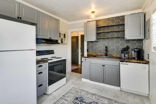 a kitchen with white appliances and gray cabinets at Cozy Starkville Apartment Walk to Main Street! in Starkville