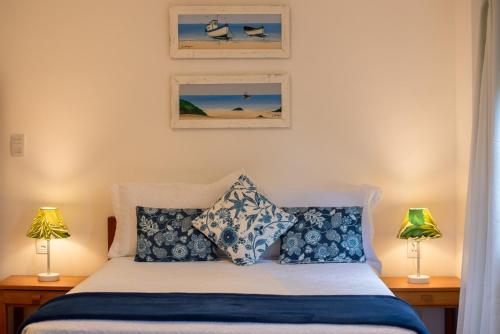 a bedroom with a bed with blue and white pillows at Villa Bella Ferradura in Búzios