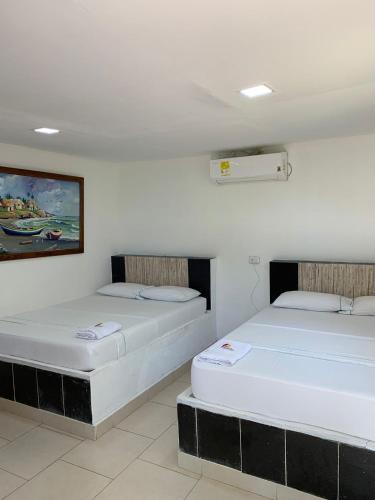 two beds sitting in a room with at Hotel Agroturistico Palma Vino in Arboletes