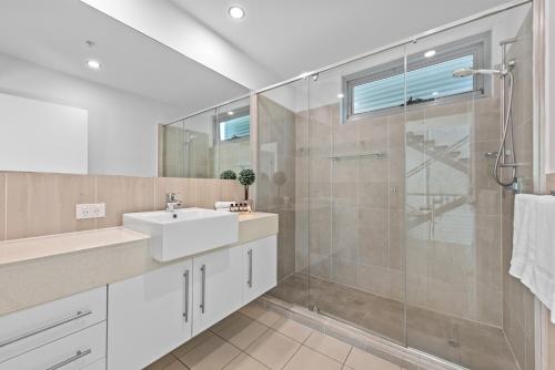 a bathroom with a sink and a glass shower at Proximity Waterfront Apartments in Redcliffe