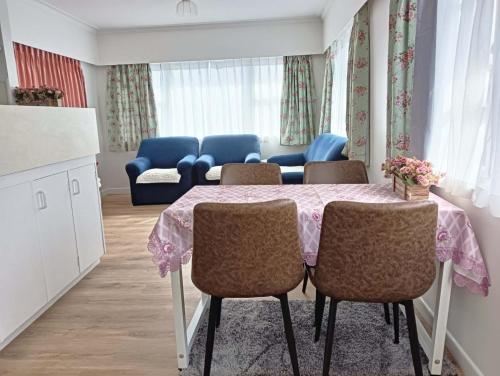a dining room with a table with chairs and a couch at Melville Guest House near Waikato Hospital in Hamilton