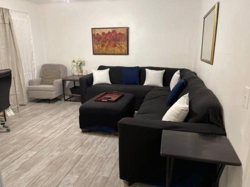 sala de estar con sofá negro y silla en Comfort & Quiet in a central location, en Elizabeth City
