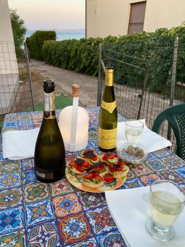 a table with three bottles of wine and a plate of food at Casa Frontemare in Carloforte
