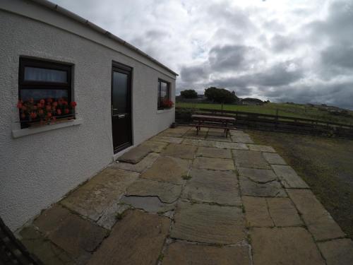 a building with a bench and a window with fruit on it at Madras cottage Orkney Islands in Harray