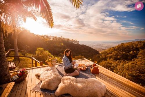 a woman sitting on a deck with two stuffed animals at Pousada Caminho dos Canyons in Praia Grande