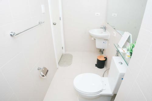 a white bathroom with a toilet and a sink at Resort Condo Unit with Stunning View - Azure North in Lagundi