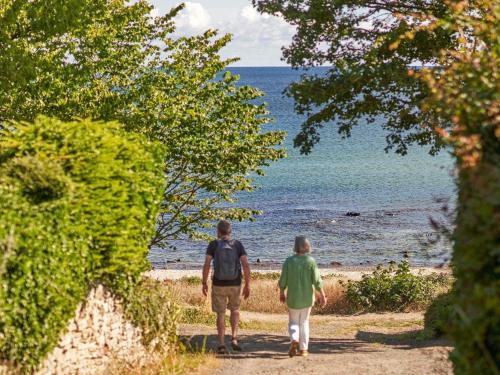 two people walking down a path towards the beach at Seaside Bliss in Sandkas - By Traum Ferienwohnungen in Allinge