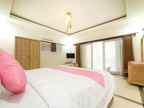 a bedroom with a large bed with a pink pillow at Dzawani Villa Kerobokan in Kerobokan