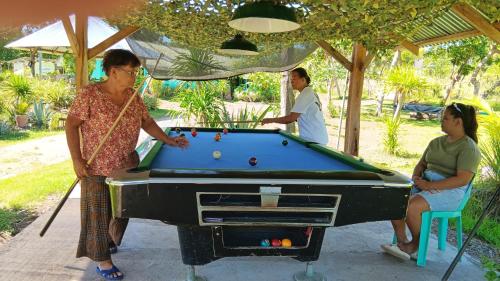 a group of people playing a game of pool at House of TamSe Laagans ' Inn in Badian