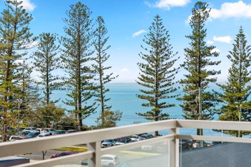 a view of the ocean from a balcony with trees at Proximity Waterfront Apartments in Redcliffe