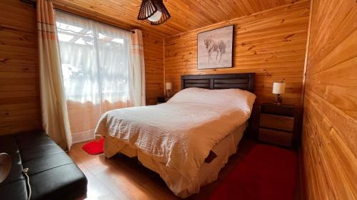 1 dormitorio con 1 cama en una cabaña de madera en Cabaña Vista Bella, en Pelluhue