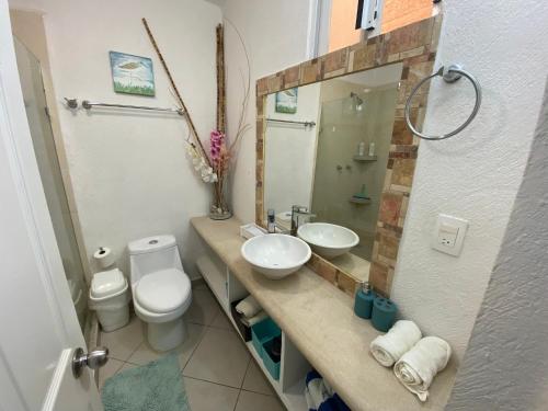 a bathroom with a sink and a toilet and a mirror at Acapulco Diamante hermoso departamento in Acapulco