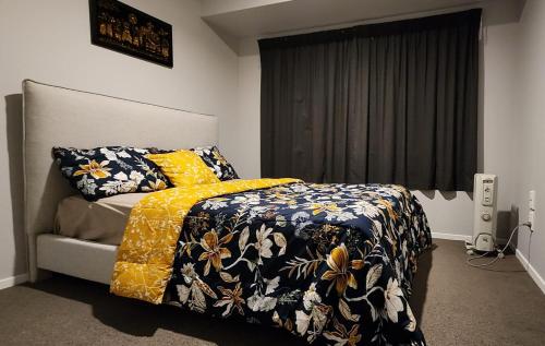 a bedroom with a bed with a yellow and blue blanket at A room in Riverstone Terraces with views - Homestay in Upper Hutt