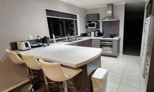 a kitchen with a white counter and chairs in it at A room in Riverstone Terraces with views - Homestay in Upper Hutt