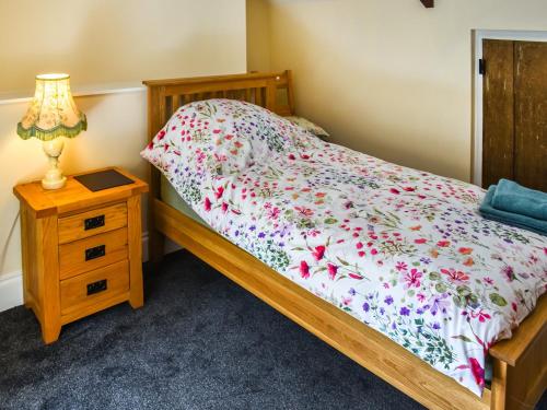 1 dormitorio con 1 cama y mesita de noche con lámpara en Carnlussack Cottage en Camborne