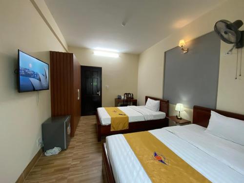 ein Hotelzimmer mit 2 Betten und einem Flachbild-TV in der Unterkunft Khách sạn HOÀ BÌNH QUẢNG TRỊ in Ðông Hà