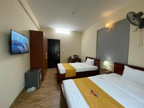 a hotel room with two beds and a flat screen tv at Khách sạn HOÀ BÌNH QUẢNG TRỊ in Ðông Hà