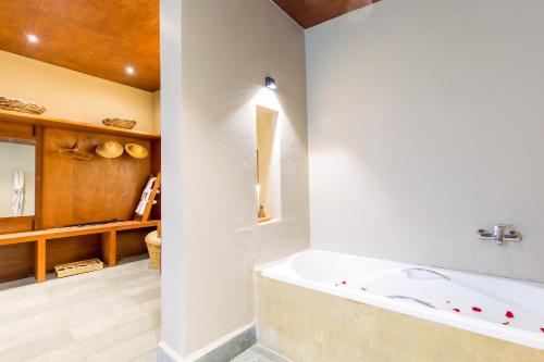 a bath tub in a bathroom with a wooden ceiling at Sanctuary Chitwan National Park in Chitwan