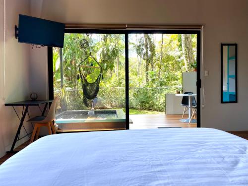 a bedroom with a bed and a view of a garden at ChicoRico Studios in Uvita