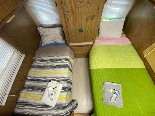 two beds in a small room with green sheets at House Rooms & RV Rooms Near LAX in Los Angeles