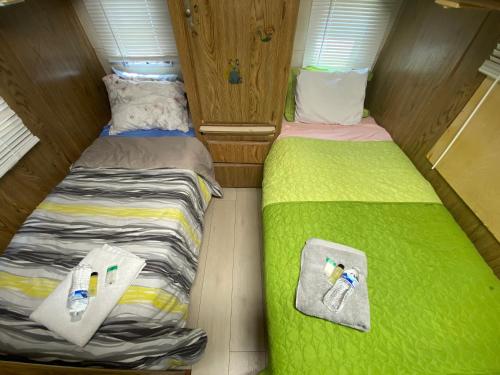 two beds in a small room with green sheets at House Rooms & RV Rooms Near LAX in Los Angeles