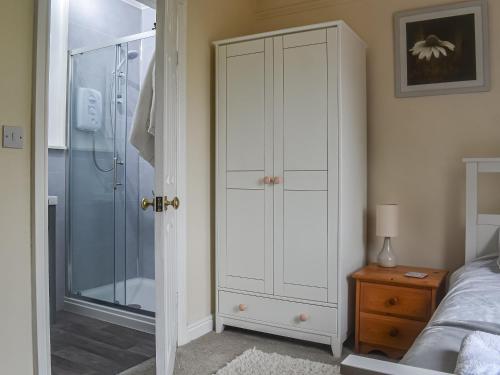 een slaapkamer met een douche en een witte kast bij Oakleigh in Rathmell
