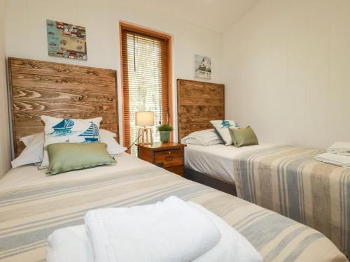 a bedroom with two beds and a window at 4 Water's Edge in Looe