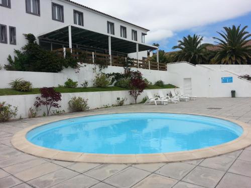 a large blue swimming pool in front of a house at Apartamentos Turisticos Nossa Senhora Da Estrela in Lagoa