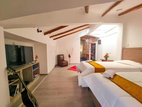 a room with three beds and a flat screen tv at Apart Hotel El Puma in Cusco