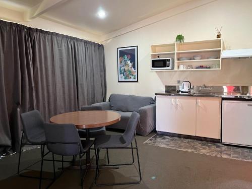 a living room with a table and a kitchen at Caves Motor Inn in Te Kuiti